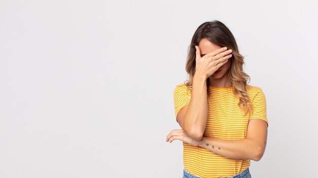 pretty thin woman looking stressed, ashamed or upset, with a headache, covering face with hand