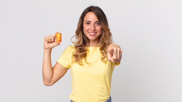 Pretty thin woman pointing at camera choosing you and holding batteries