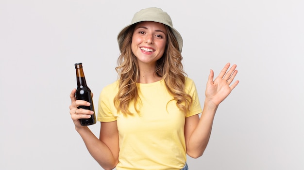 Pretty thin woman smiling happily, waving hand, welcoming and greeting you and holding a beer. summer concept