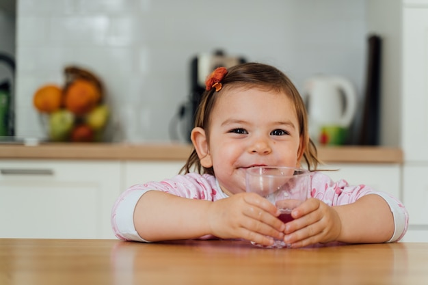 かなり幼児の子供がスナックを食べ、ジュースのガラスを飲む