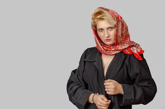 Photo pretty topless blonde girl in a black raincoat and colored scarf hand near face looking at camera