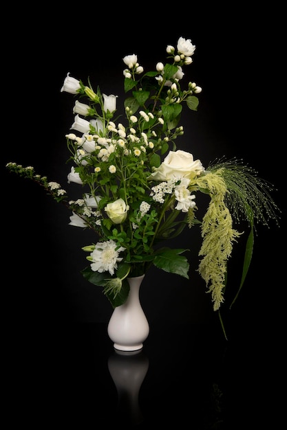 黒の背景に白い花瓶のきれいな白い花の花束
