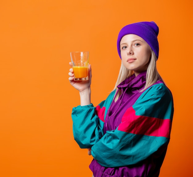 Photo pretty woman in 90s tracksuit with pumpkin juice on orange