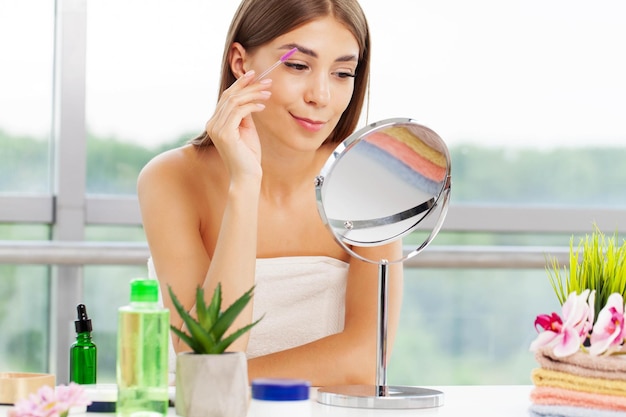 Pretty woman applies makeup in the bathroom of elite apartment