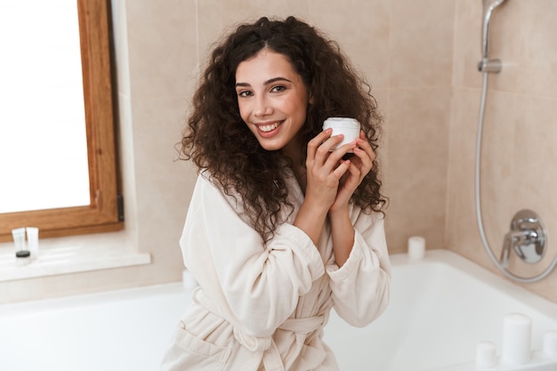 Pretty woman in bathroom take care of her skin.