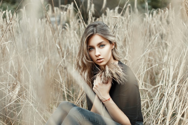 Pretty woman in black shirt sitting in a millet field