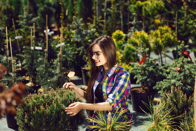 Милая женщина выбирая и покупая зеленые растения для сада.