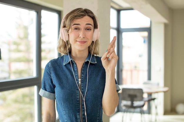 写真 きれいな女性が指を交差させ、幸運のヘッドフォンと音楽のコンセプトを願っています