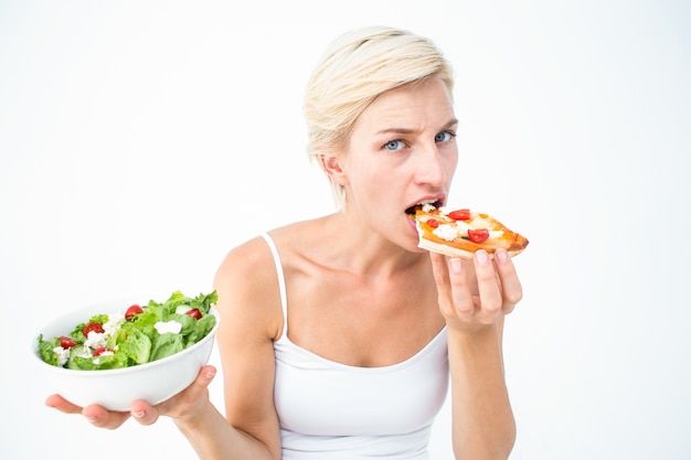 Donna graziosa che decide di mangiare la pizza piuttosto l'insalata