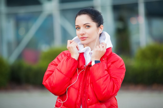 Pretty woman doing fitness outdoors listening to music