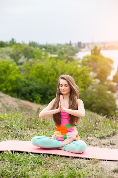 Photo pretty woman doing yoga exercises on nature landscape