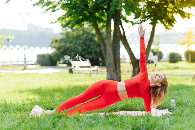 Pretty woman doing yoga exercises in the park