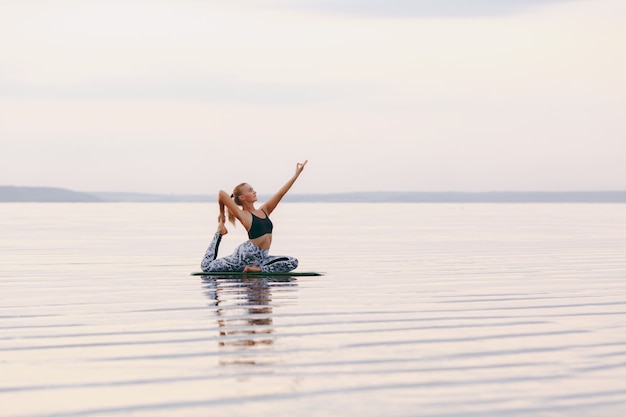 The pretty woman doing yoga at sunset outdoors