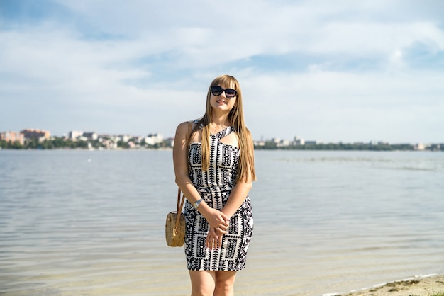 Pretty woman in dress near lake, summer time