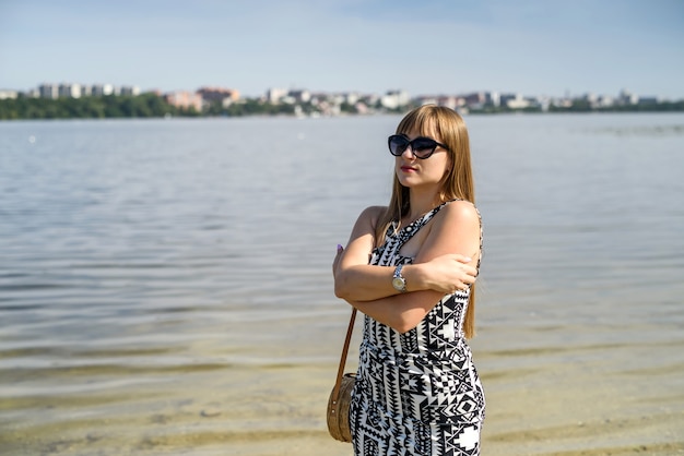 Pretty woman in dress near lake, summer time