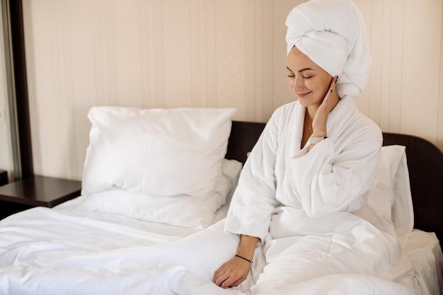 Pretty woman dressed in bathrobe and tovel on her head relax on the bed