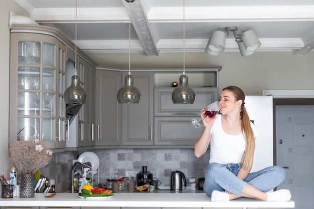 Pretty woman drinking some wine at home in kitchen