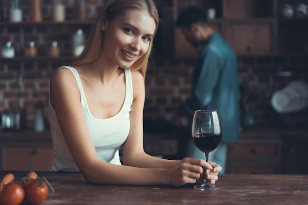 Pretty woman drinking some wine at home in kitchen