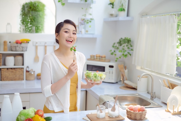 Photo pretty woman eating a salad in the kitchen