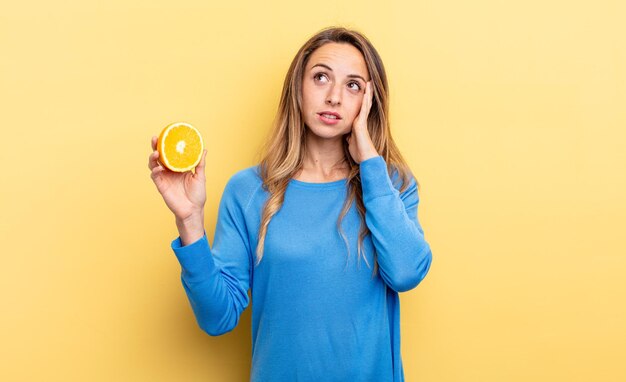 Pretty woman feeling bored, frustrated and sleepy after a tiresome holding half orange