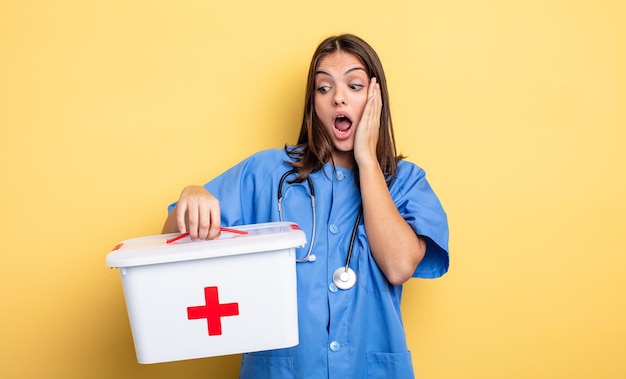 Photo pretty woman feeling happy, excited and surprised. nurse with with a first aid kit nurse