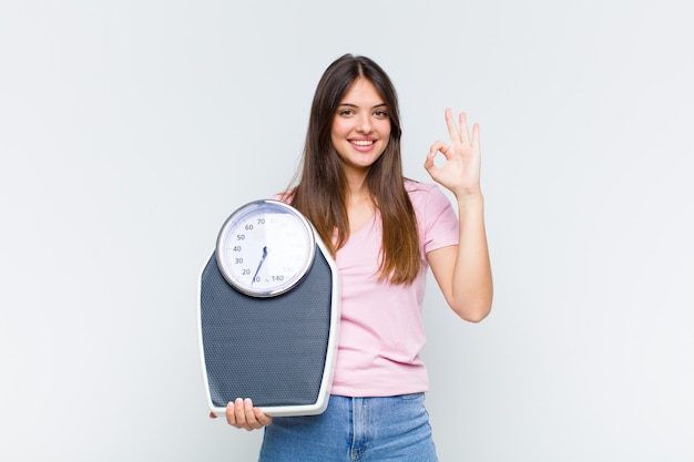 Pretty woman feeling happy, relaxed and satisfied, showing approval with okay gesture, smiling