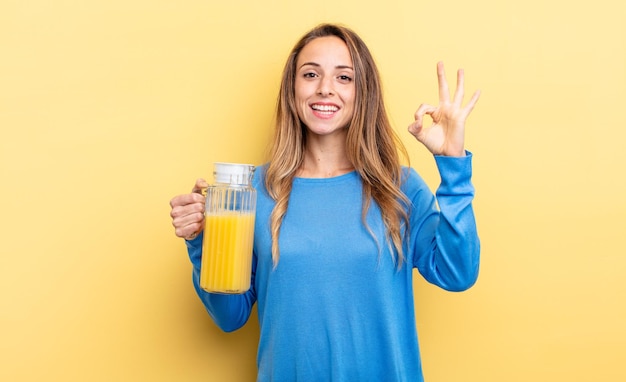 pretty woman feeling happy, showing approval with okay gesture orange juice concept