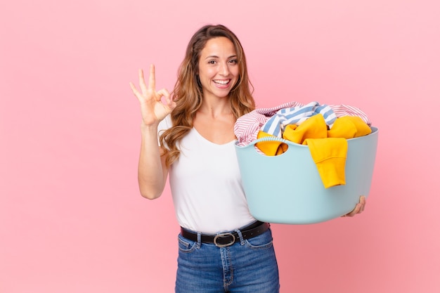 Pretty woman feeling happy, showing approval with okay gesture and washing clothes.