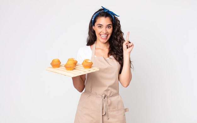 pretty woman feeling like a happy and excited genius after realizing an idea and holding a muffins tray
