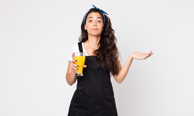 Pretty woman feeling puzzled and confused and doubting and holding an orange juice glass