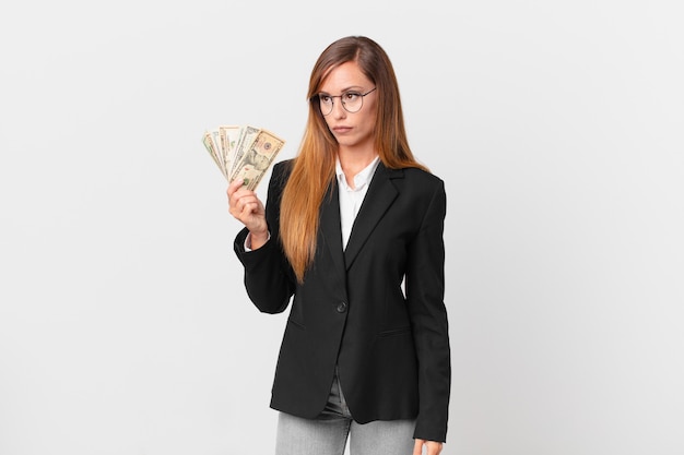 Pretty woman feeling sad, upset or angry and looking to the side. business and dollars concept