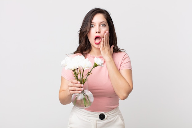 Pretty woman feeling shocked and scared and holding a decorative flowers pot