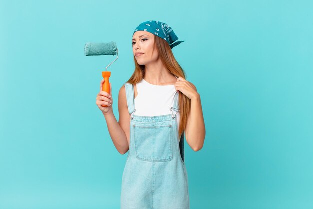 Bella donna che si sente stressata, ansiosa, stanca e frustrata dipingendo un nuovo muro di casa