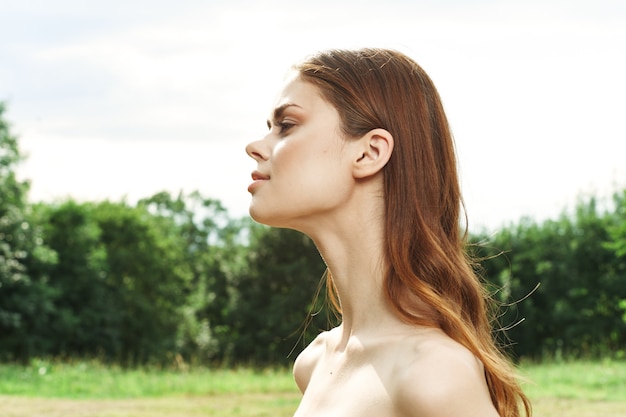 Pretty woman in a field outdoors bare shoulders clear skin cropped view