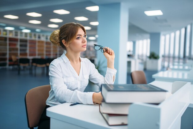 Pretty woman in glasses learning book, library