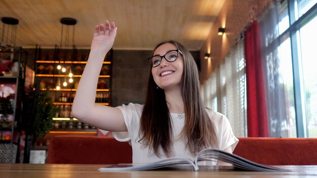 Bella donna con gli occhiali leggendo il menu e facendo un ordine.