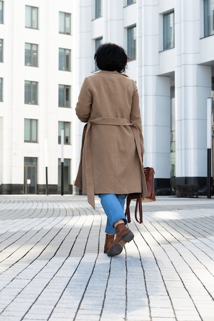 Pretty woman goes to work in a business center in stylish clothes down the street.