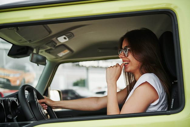 Pretty woman in the green modern car posing for the camera.