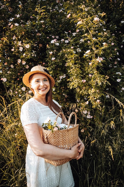 Pretty woman in hat holding basket with flowers