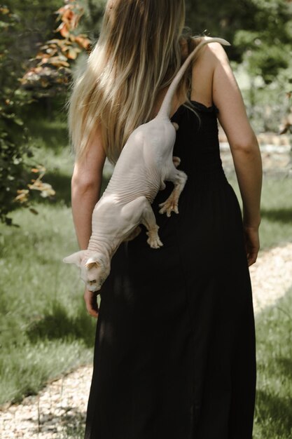 Pretty woman at her 30s in the garden with white sphinx\
cat