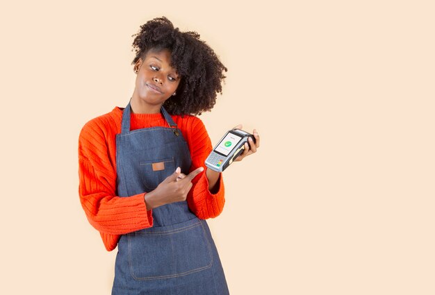 Pretty woman, hispanic curly hair, charges with card payment, beige background