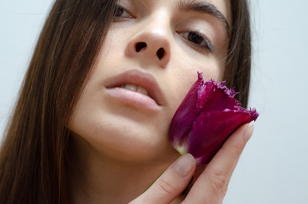 Foto bella donna che tiene un tulipano viola