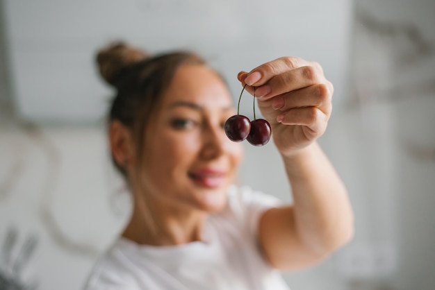 Pretty woman holds cherries in her hand with a focus on a berry