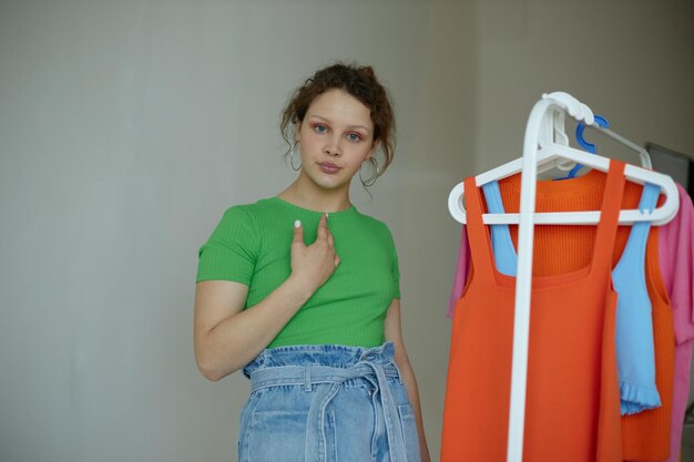 Photo pretty woman ironing clothes on a hanger wardrobe light background unaltered