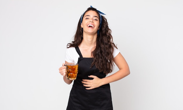 Красивая женщина громко смеется над какой-то веселой шуткой и держит пинту пива