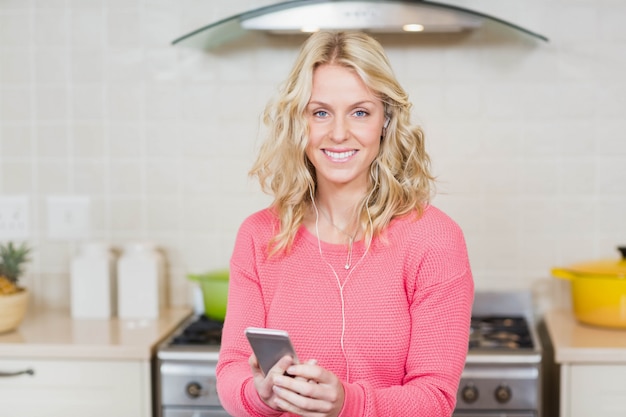 Pretty woman listening to music with headphones in the kitchen