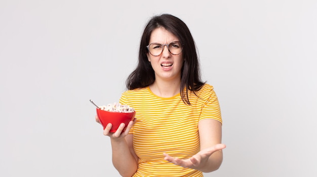 Pretty woman looking angry, annoyed and frustrated and holding a breakfast bowl