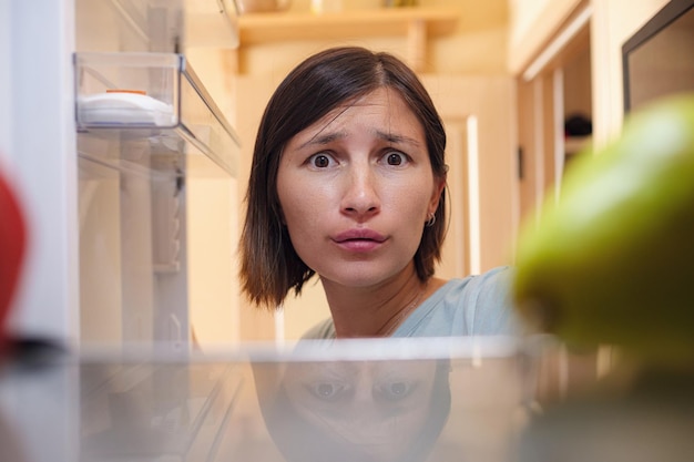 Foto donna graziosa in cerca di cibo in frigorifero