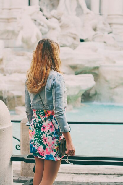 Donna graziosa che osserva alla fontana di trevi durante il suo viaggio a roma