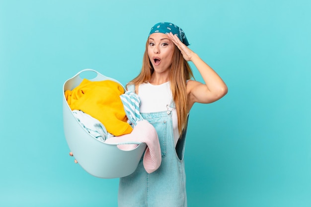 Pretty woman looking happy, astonished and surprised holding a wash basket